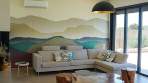 Una sala de estar moderna con un sofá modular, una mesa de centro de madera y un ventanal con vistas a zonas verdes.