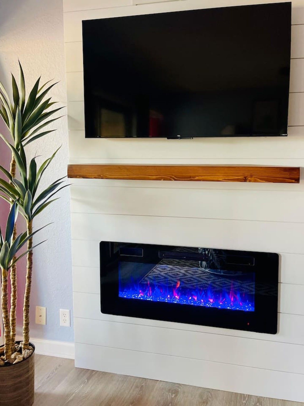 A flat-screen TV mounted above a fireplace with a built-in TV display.