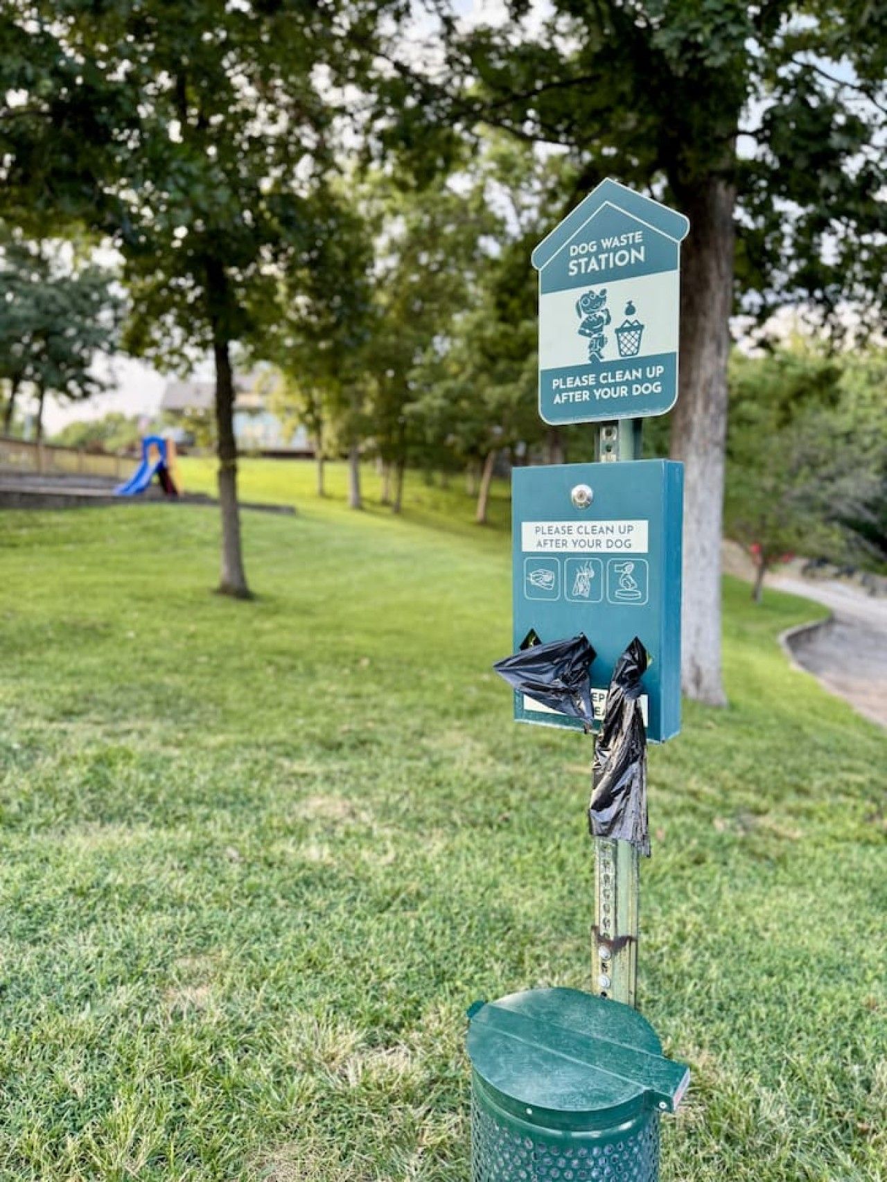 Una estación para desechar residuos caninos con un letrero que indica limpiar después de tu perro.
