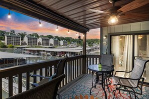 A balcony with a view of a marina and buildings, furnished with chairs and a table. - Boho Flamingo-Pools, Hot Tub, Pet Friendly (Village of Four Seasons)