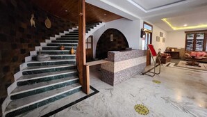 Un vestíbulo de hotel con una escalera de mármol, una recepción y un área de estar.