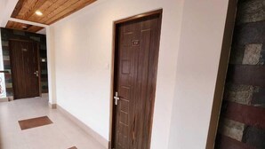 Un pasillo con techo de madera, pared de piedra y una puerta con placa de número.