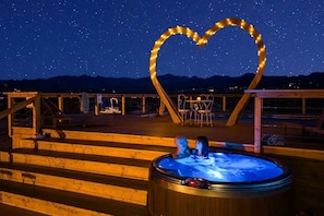 A hot tub with a heart-shaped light decoration, wooden steps, and a view of the mountains at night. - The White Owl House ☆pool ☆private ☆gorgeous views (Joshua Tree)