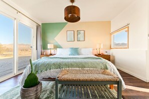A bedroom with a bed, a bench, a potted plant, and a view of the desert. - The White Owl House ☆pool ☆private ☆gorgeous views (Joshua Tree)