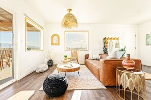 A modern living room with a brown sofa, a round coffee table, and a large window. - The White Owl House ☆pool ☆private ☆gorgeous views (Joshua Tree)