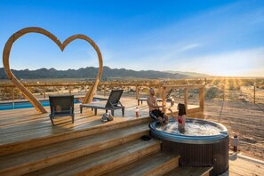 Una terraza de madera con sillas de descanso, un jacuzzi y una piscina.