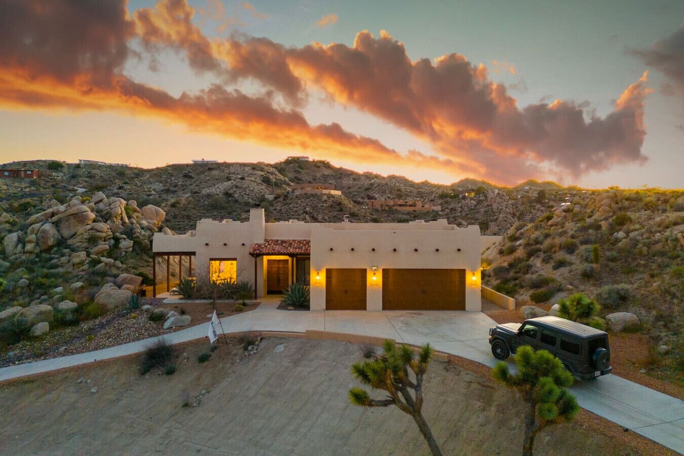 A modern house with a garage, surrounded by a desert landscape.