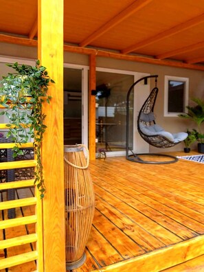 A wooden deck with a hanging chair, a woven basket, and a plant. - Mobile Home Nensi (Biograd na Moru)