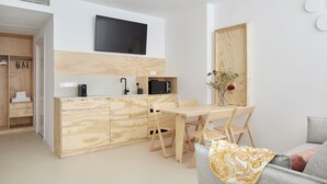 A modern kitchen with wooden cabinetry, a dining table, and a flat-screen TV mounted above the counter. - FeelFree STAYS Antiguo (San Sebastián)