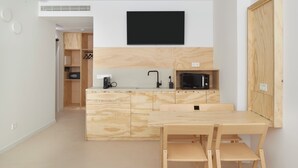 A compact kitchen with a wooden countertop, a microwave, a sink, and a black flat-screen TV mounted on the wall. - FeelFree STAYS Antiguo (San Sebastián)