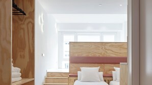 A modern bedroom with a wooden headboard, a bed with white linens, and a built-in wardrobe. - FeelFree STAYS Antiguo (San Sebastián)