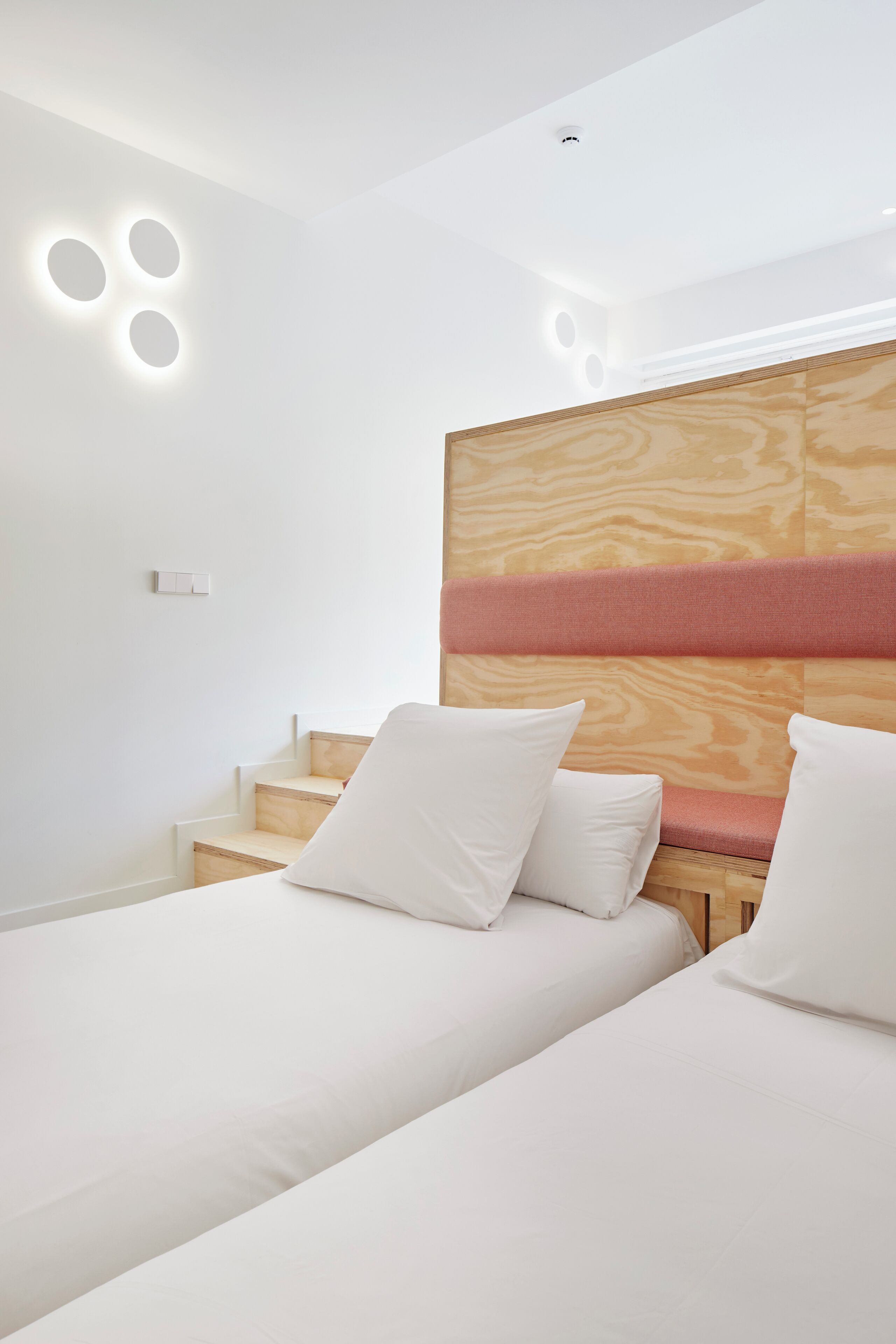 Una habitación de hotel moderna con dos camas, un cabecero de madera y una escalera.