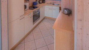 Cocina compacta con paredes de madera, tragaluz y electrodomésticos básicos.