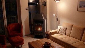 A living room with a fireplace, a red armchair, a beige sofa, and a wooden coffee table.
