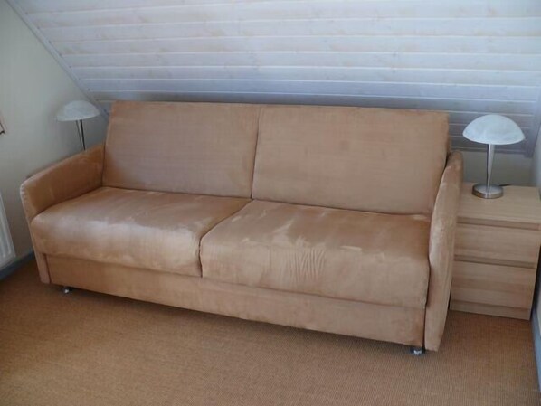 A tan leather sofa with a wooden side table and two lamps.