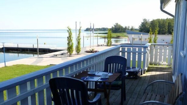 A wooden deck with a table and chairs overlooking a body of water.