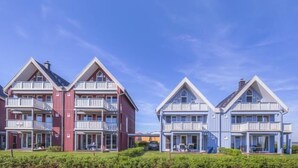 Eine Reihe von zweistöckigen Gebäuden mit Balkonen, vermutlich Teil eines Wohnkomplexes.