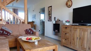 Ein Wohnzimmer mit einem Holztisch, einer Couch, einem Fernseher und einem Schrank.
