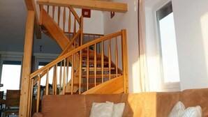 A living room with a wooden staircase, a brown sofa, and a coffee table.