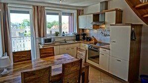 A compact kitchen with a dining area, a microwave, a stove, and a refrigerator.