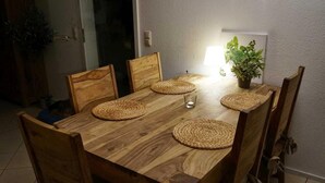 A wooden dining table with woven placemats, six wooden chairs, and a potted plant on the table.