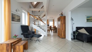 A spacious living area with a staircase, wooden furniture, and a dining area in the background.
