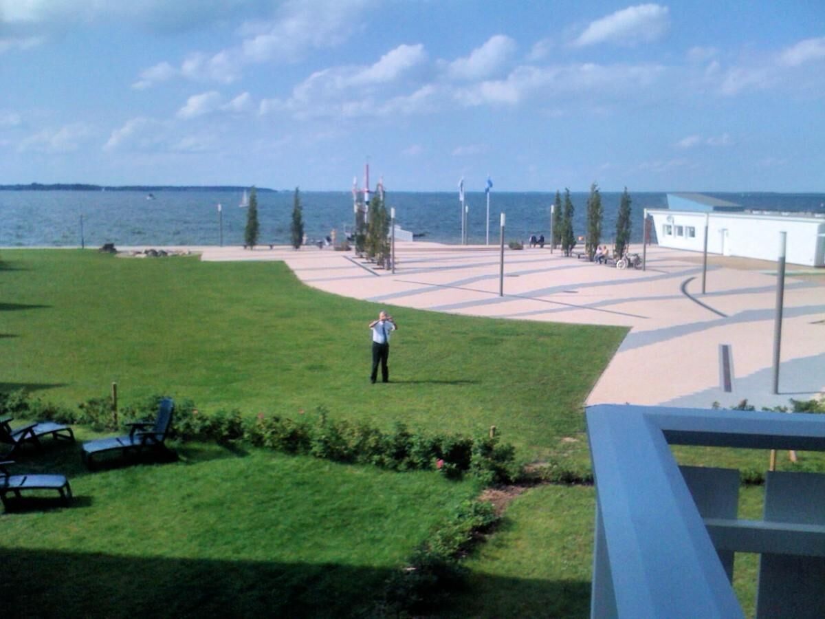 A grassy area with a person standing, a pathway, and a building in the background.