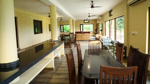 Un grand espace dédié à la salle à manger, avec une longue table et des chaises, un comptoir de bar et un coin salon comprenant un canapé et des fauteuils.
