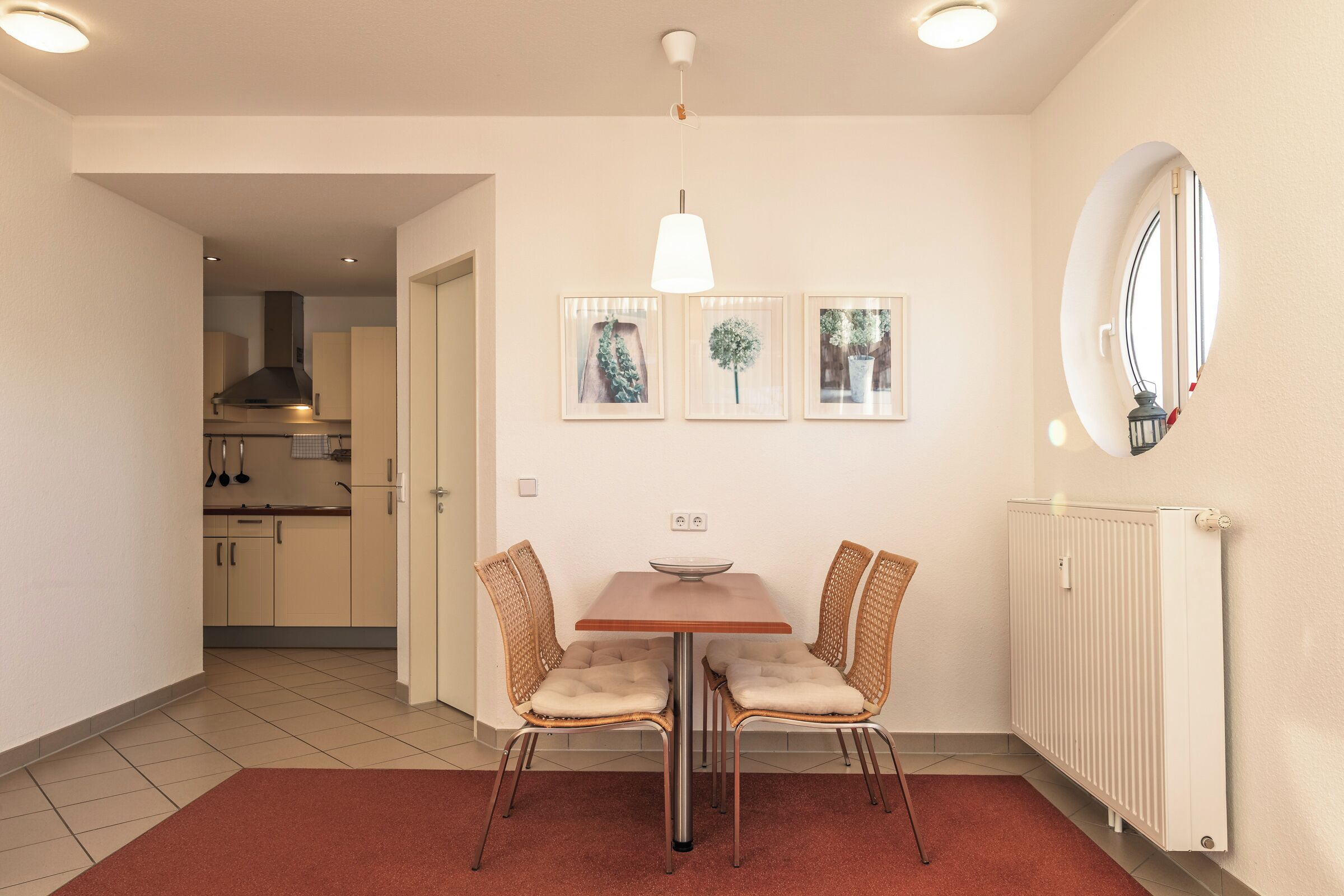 Ein Essbereich mit Tisch und Stühlen, einer Hängelampe und gerahmten Bildern an der Wand.
