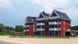En röd byggnad med flera balkonger, belägen nära en sandstrand.