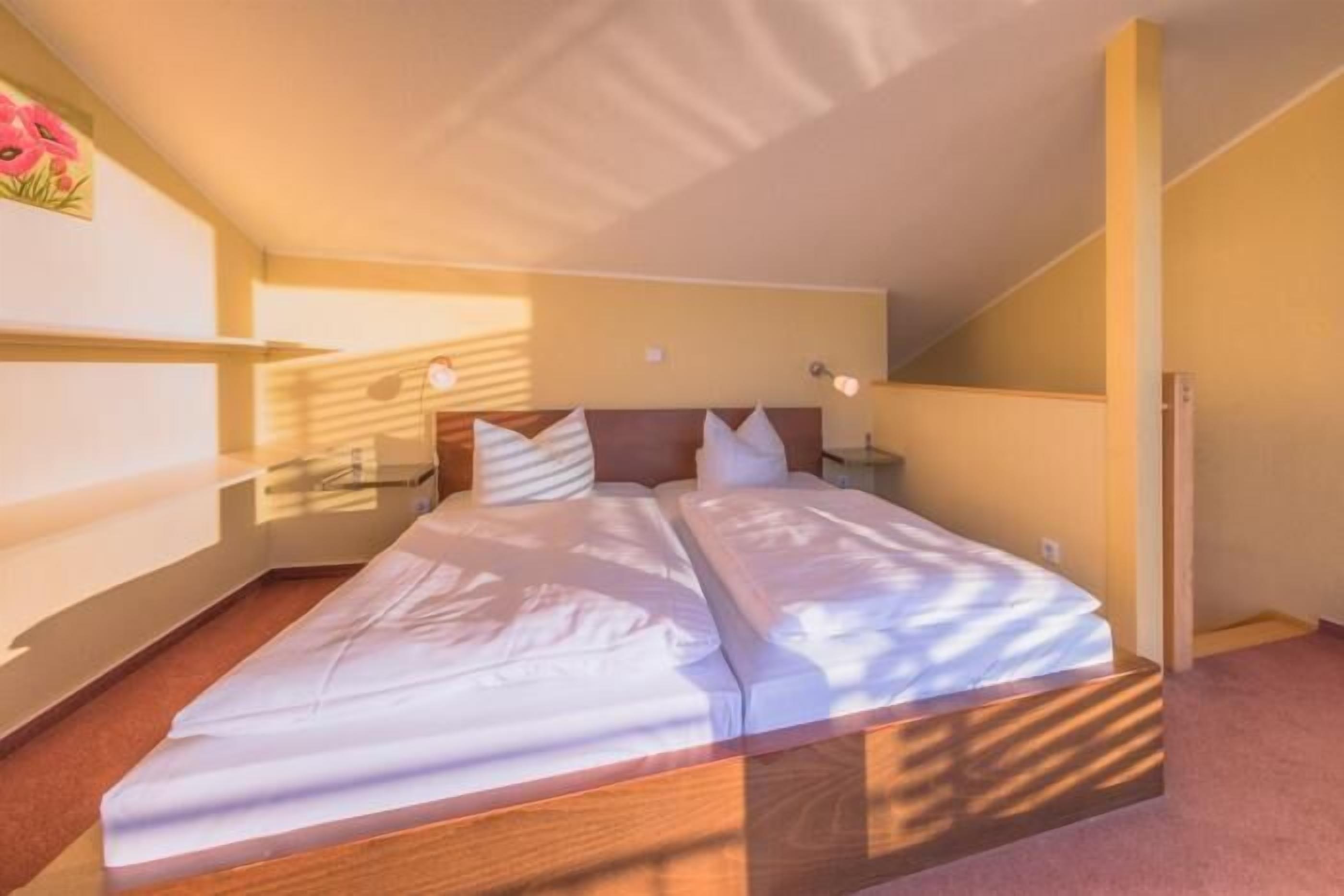 Un dormitorio con cama, mesitas de noche y una ventana.