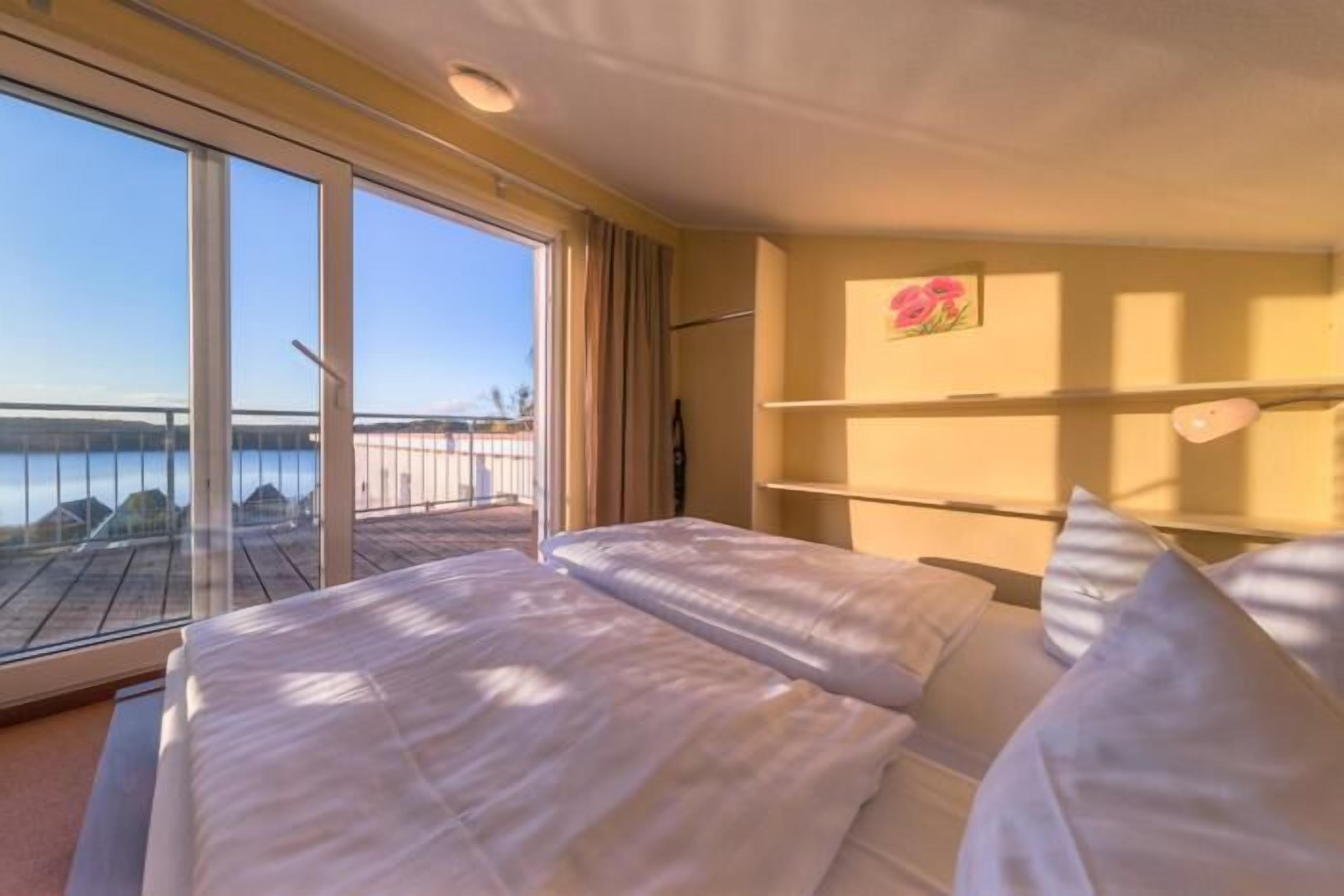 Ein Hotelzimmer mit zwei Betten, einem großen Fenster mit Meerblick und einem Regal mit Dekoration.