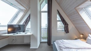 Un dormitorio con una cama, un escritorio con computadora y una ventana.