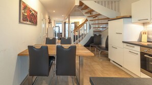Una cocina moderna con armarios blancos, una mesa de comedor de madera y sillas negras.