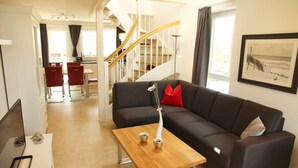 Un salon moderne avec un canapé foncé, une table basse en bois et un escalier en arrière-plan.