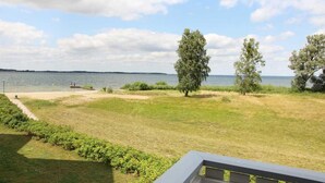 Une zone herbeuse offrant une vue sur une étendue d’eau et des arbres.