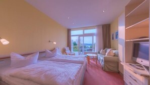 Ein Hotelzimmer mit zwei Betten, einem Fernseher, einem Schreibtisch und Blick ins Freie.