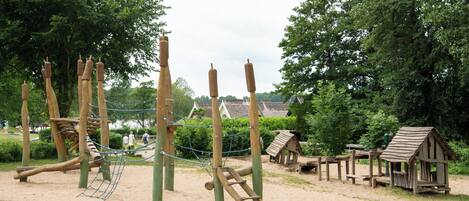 Ein Spielplatz mit Klettergeräten und einem hölzernen Spielhäuschen.