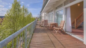 A wooden deck with outdoor furniture, a metal railing, and a view of greenery. - Schneeeule 201 - Gemütliches Apartment Über 2 Ebenen im Aparthotel Mirow (Mirow Ortsteil Granzow)