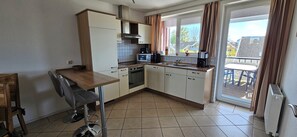 Uma cozinha compacta com área de refeições, janela com cortinas e vista para o exterior.
