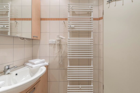 Une salle de bain équipée d’un lavabo, d’un miroir, d’un porte-serviettes et d’un téléphone fixé au mur.