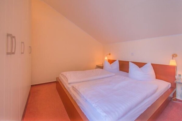 A hotel room with a single bed, two bedside tables, and a nightstand.