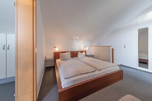 A modern bedroom with a large bed, bedside tables, and a wardrobe.
