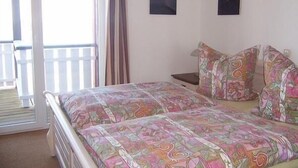 A bedroom with a bed, two pillows, a nightstand, and two framed pictures on the wall.