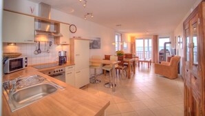 A modern kitchen with a dining area, large windows, and a view of the outdoors.