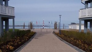 A paved pathway leading to a waterfront area with a lighthouse in the distance.