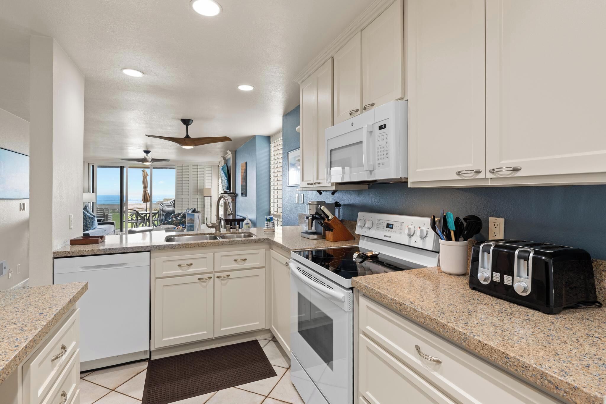 A modern kitchen with white cabinets, a microwave, a stove, and a toaster.