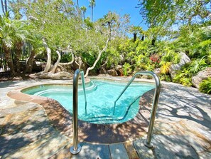 A swimming pool with a tiled edge, surrounded by a stone deck and lush greenery. - D27 North Coast Village - Oceanfront, ground level cottage, Amazing Direct Ocean Views (Oceanside)