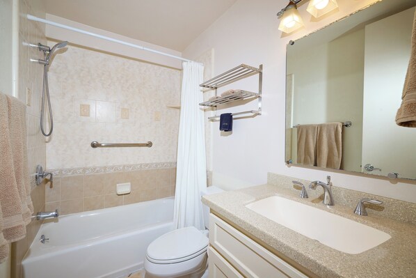 A bathroom with a bathtub, toilet, sink, and a mirror.