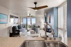 A modern kitchen with a granite countertop, stainless steel sink, and a ceiling fan. - D27 North Coast Village - Oceanfront, ground level cottage, Amazing Direct Ocean Views (Oceanside)